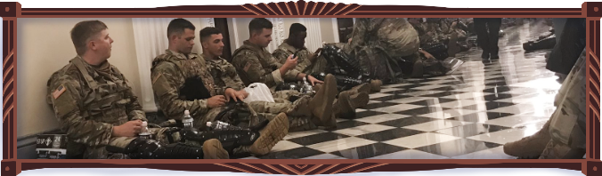 National Guard soldiers sit in a brightly lit White House hallway eating snacks and drinking plastic bottled water as they wait the rain out. They all look young. A couple of them are on their phones.